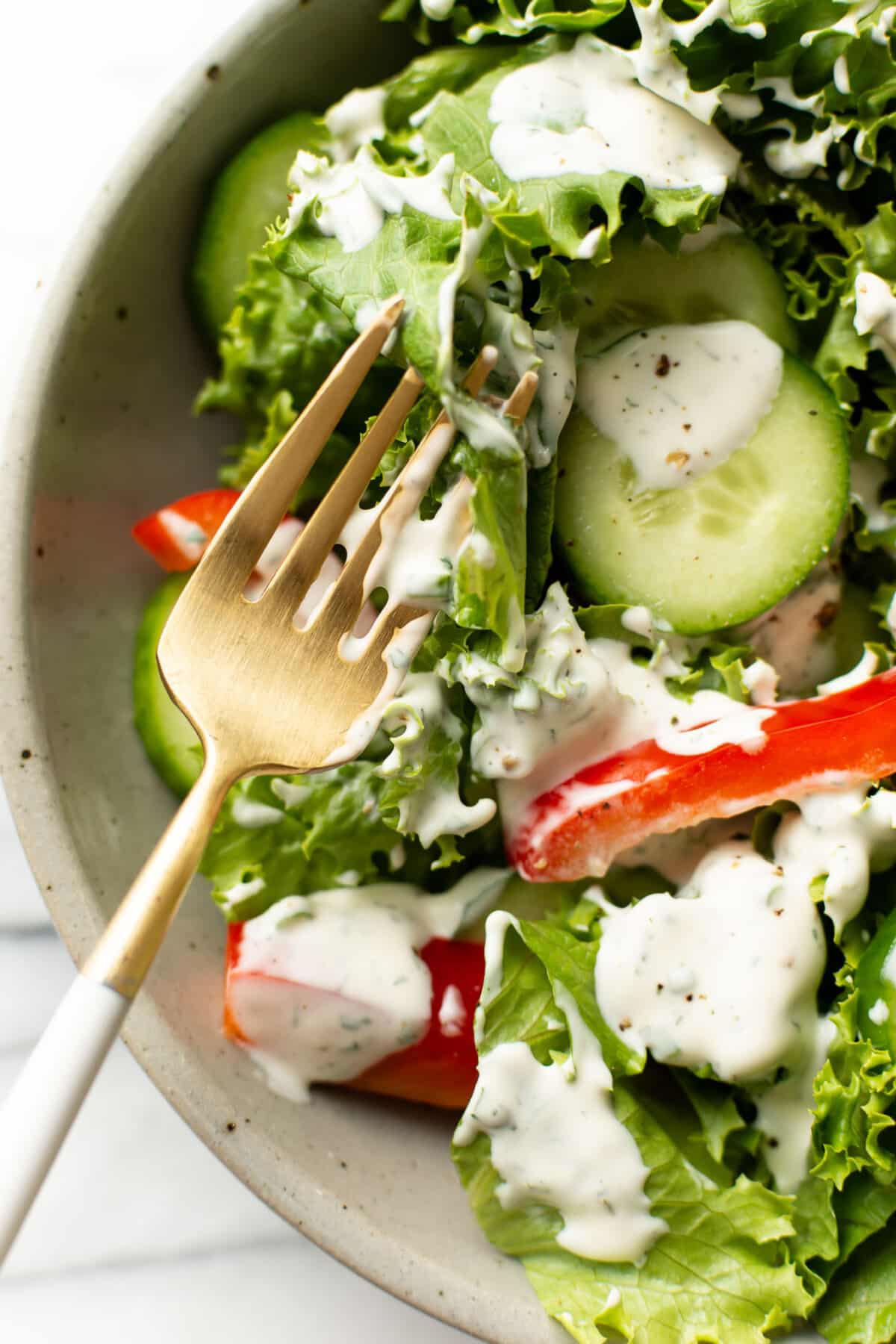 a bowl of salad with ranch dressing and a fork