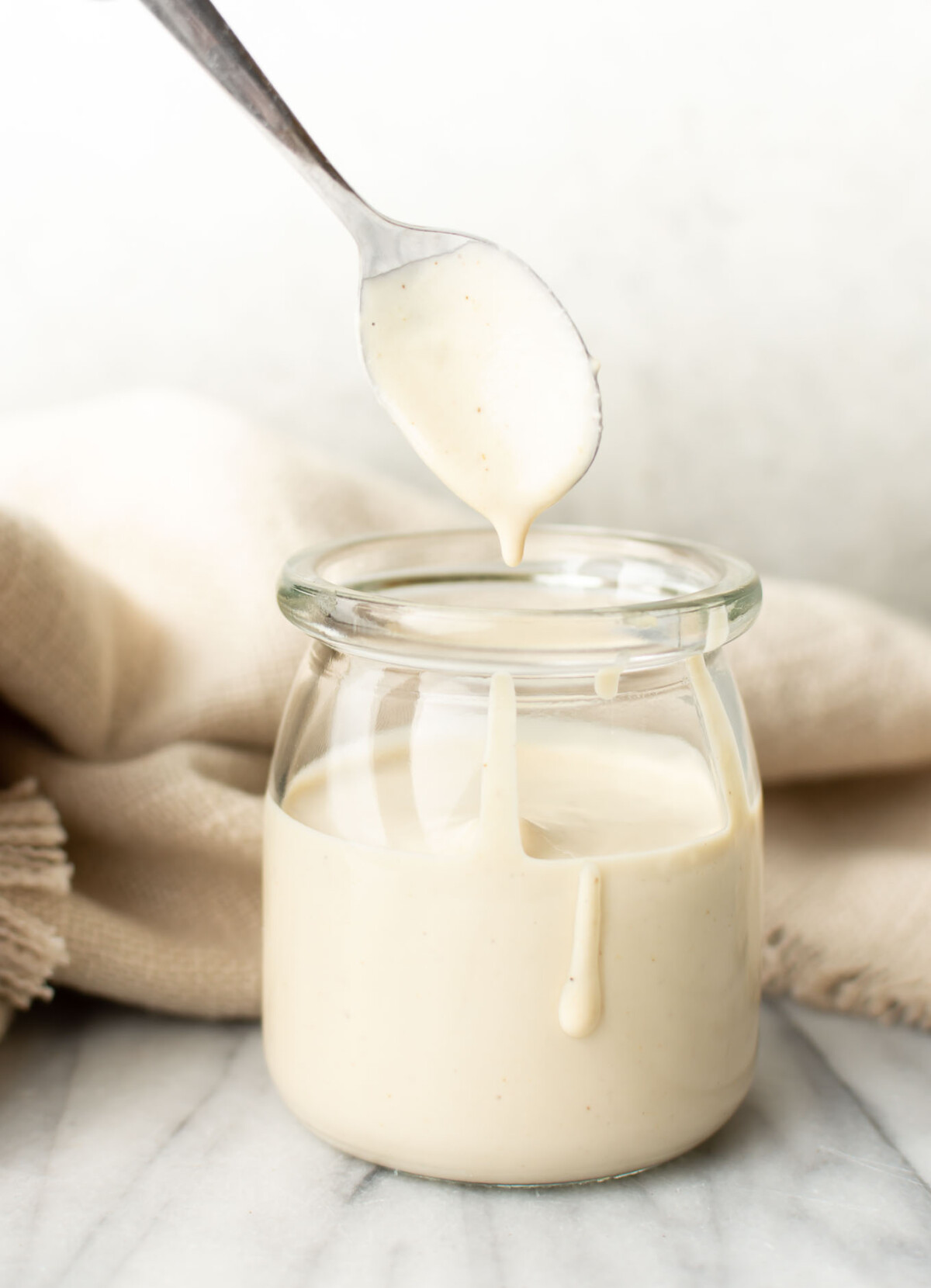 a jar with homemade lemon tahini dressing and a spoon