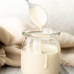 a jar with homemade lemon tahini dressing and a spoon