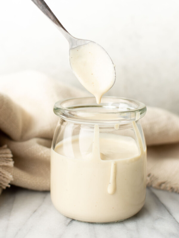 a jar with homemade lemon tahini dressing and a spoon