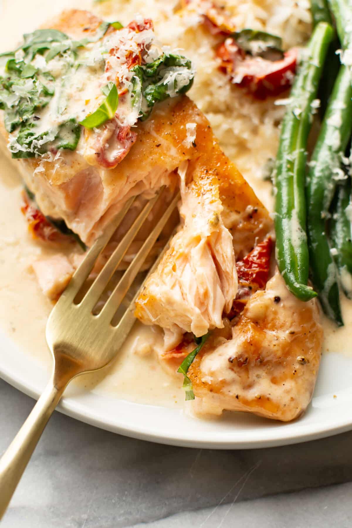 a plate with creamy tuscan salmon, green beans, rice, and a fork