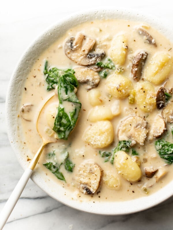 a bowl of mushroom and spinach gnocchi soup with a spoon