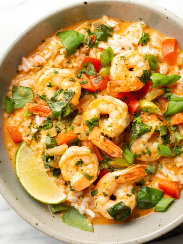 a bowl of thai shrimp curry over rice with a lime wedge