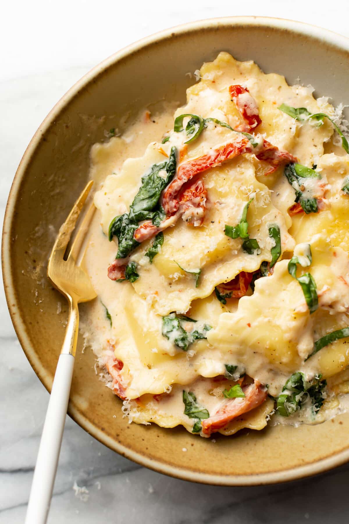 a bowl of creamy tuscan ravioli with a fork