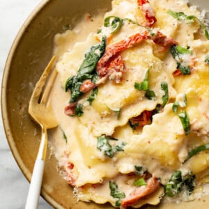 a bowl of creamy tuscan ravioli with a fork