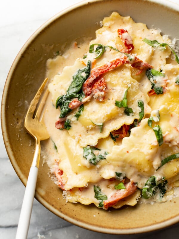 a bowl of creamy tuscan ravioli with a fork