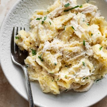 white bowl with chicken tortellini Alfredo and a fork