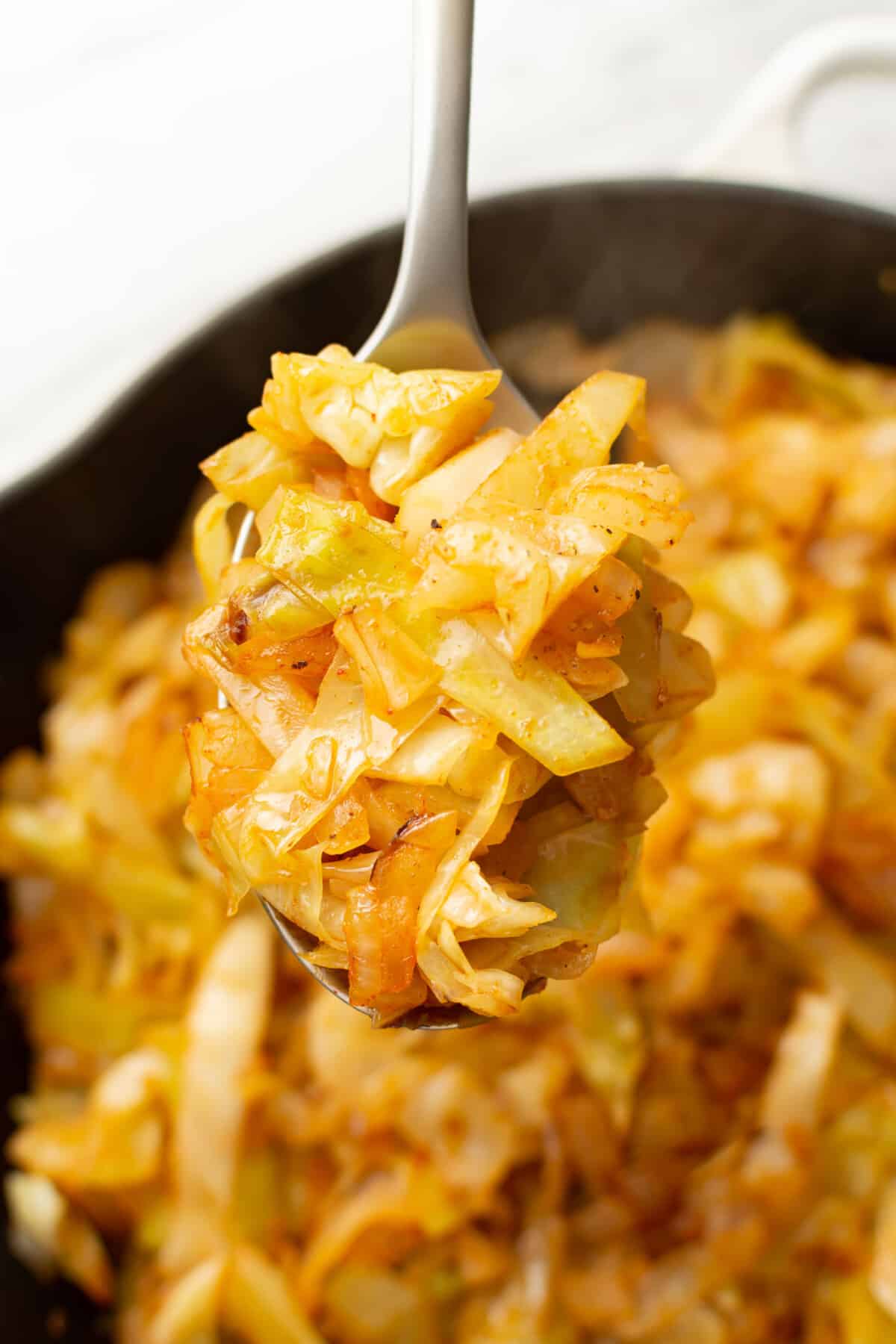 a serving spoon with sauteed cabbage