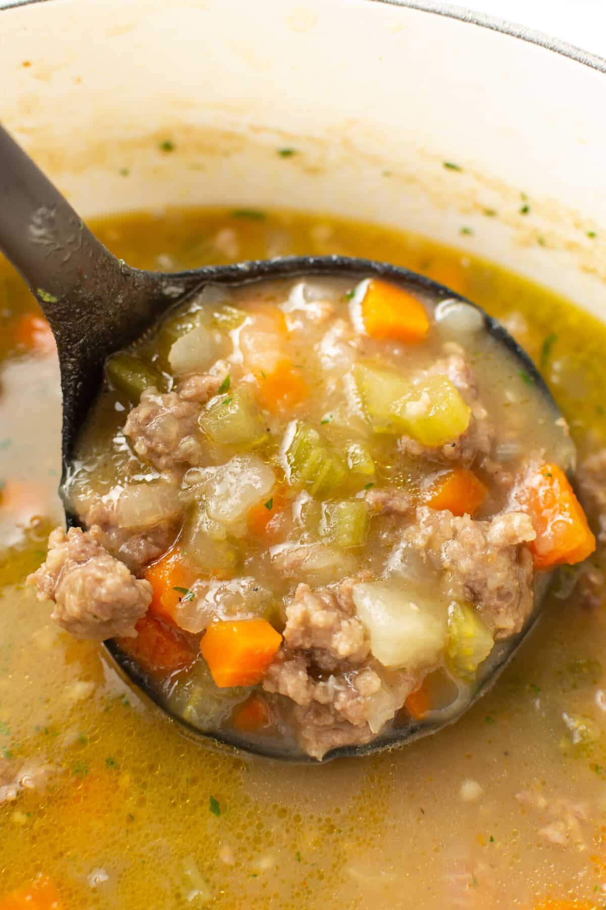 a soup pot with bratwurst soup and a ladle