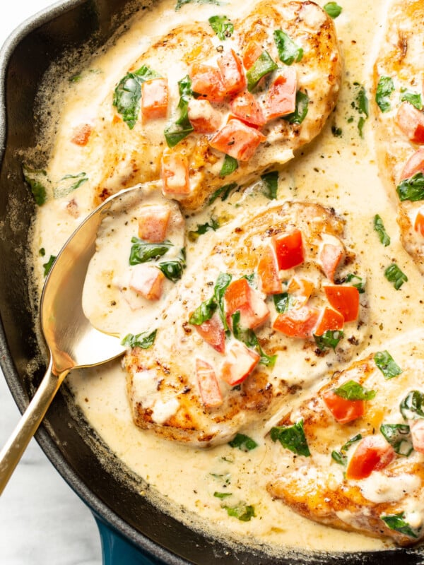 a skillet with creamy tomato basil chicken and a serving spoon