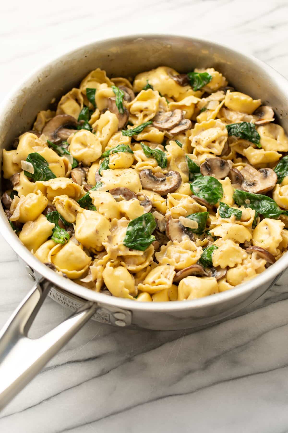 a pan with creamy tortellini with spinach and mushrooms