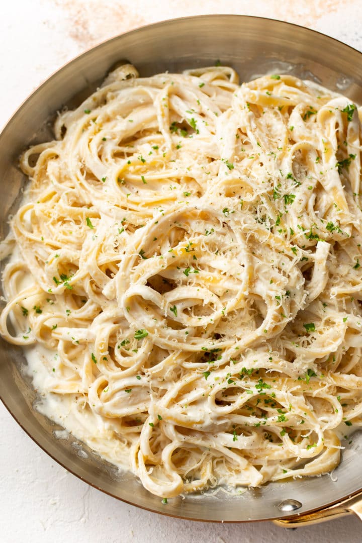 the best homemade Alfredo sauce coating fettuccine pasta in a copper skillet