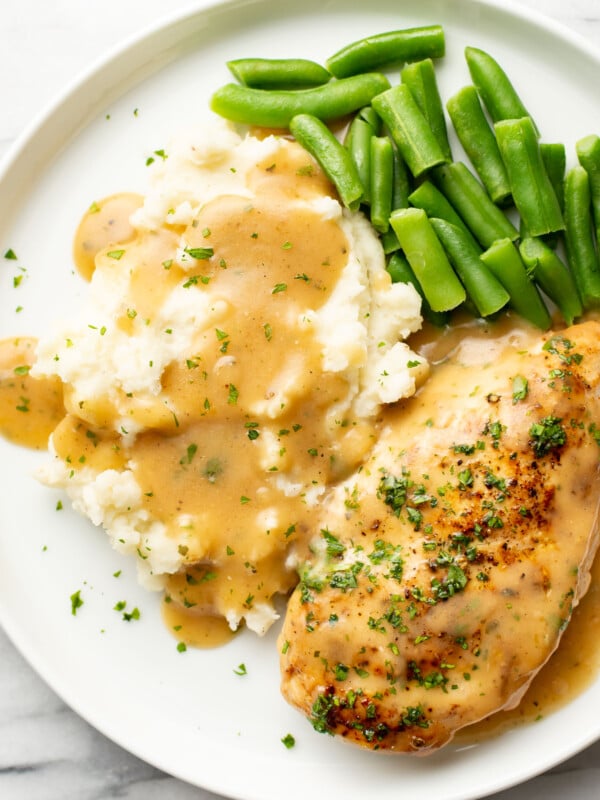 a plate with ranch chicken and gravy, green beans, and mashed potatoes