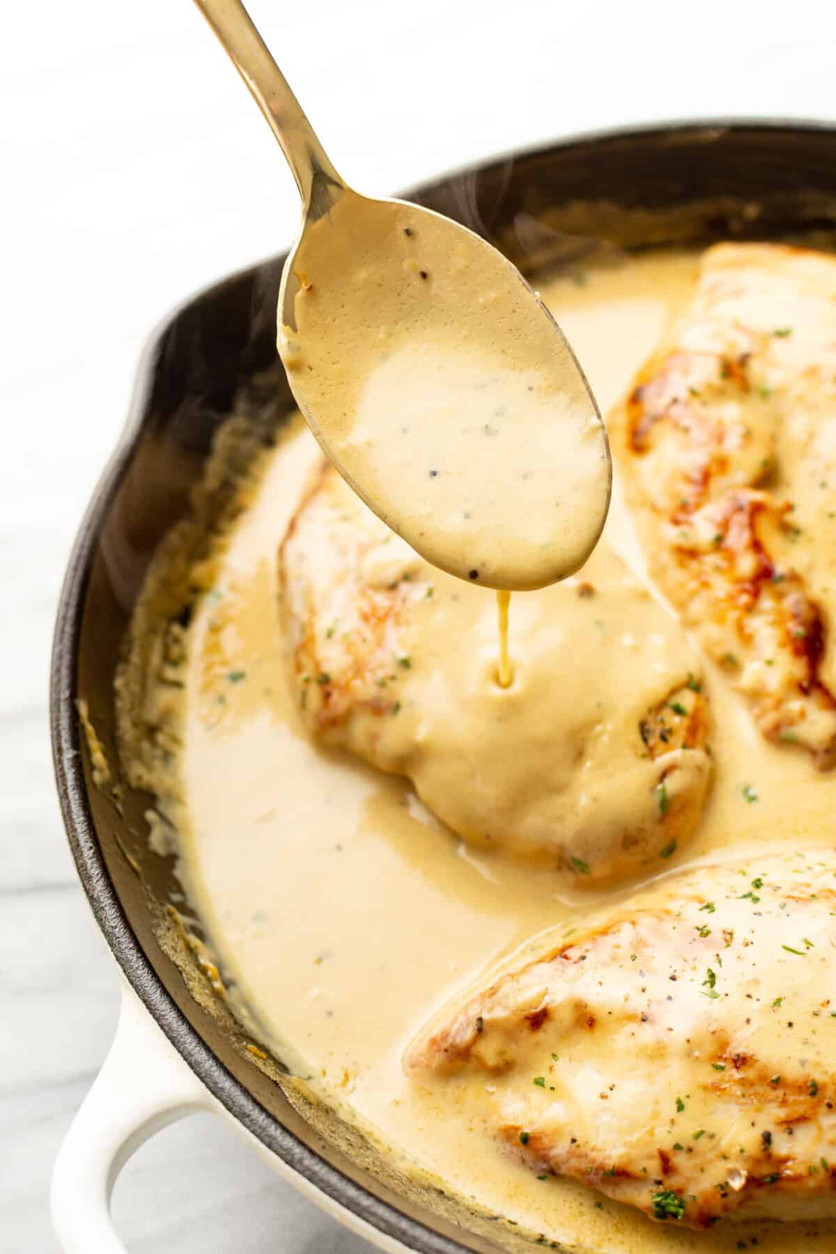 a skillet with lemon pepper chicken and a serving spoon