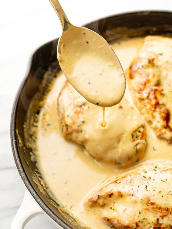 a skillet with lemon pepper chicken and a serving spoon