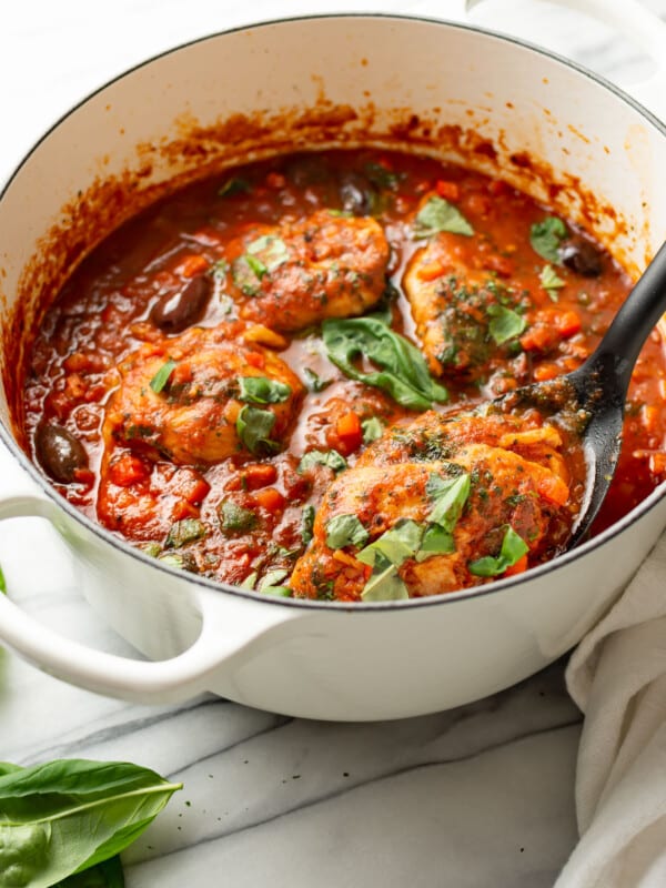 a dutch oven with chicken cacciatore and a serving spoon