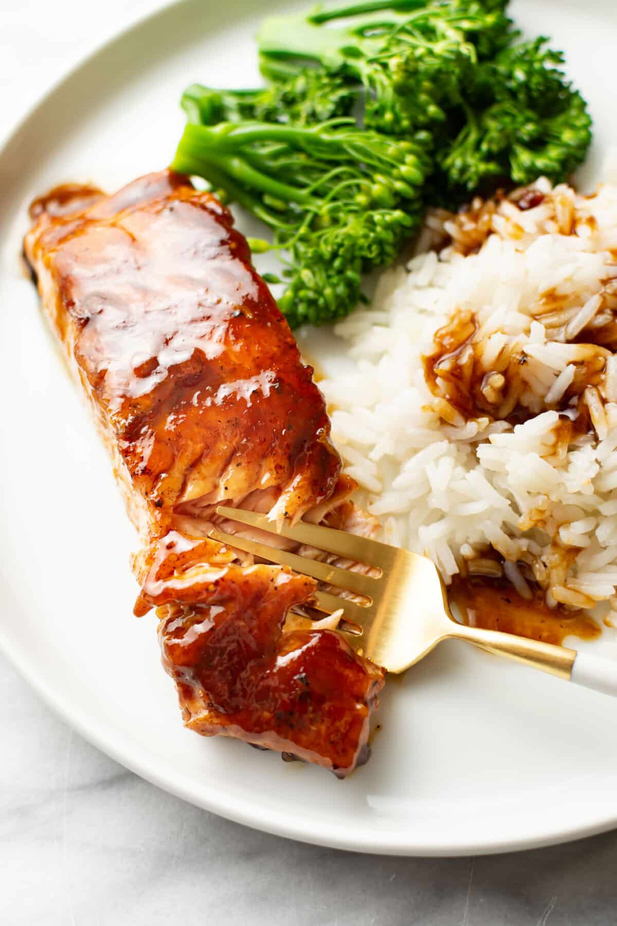 a plate with brown sugar glazed salmon, broccoli, and rice with a fork