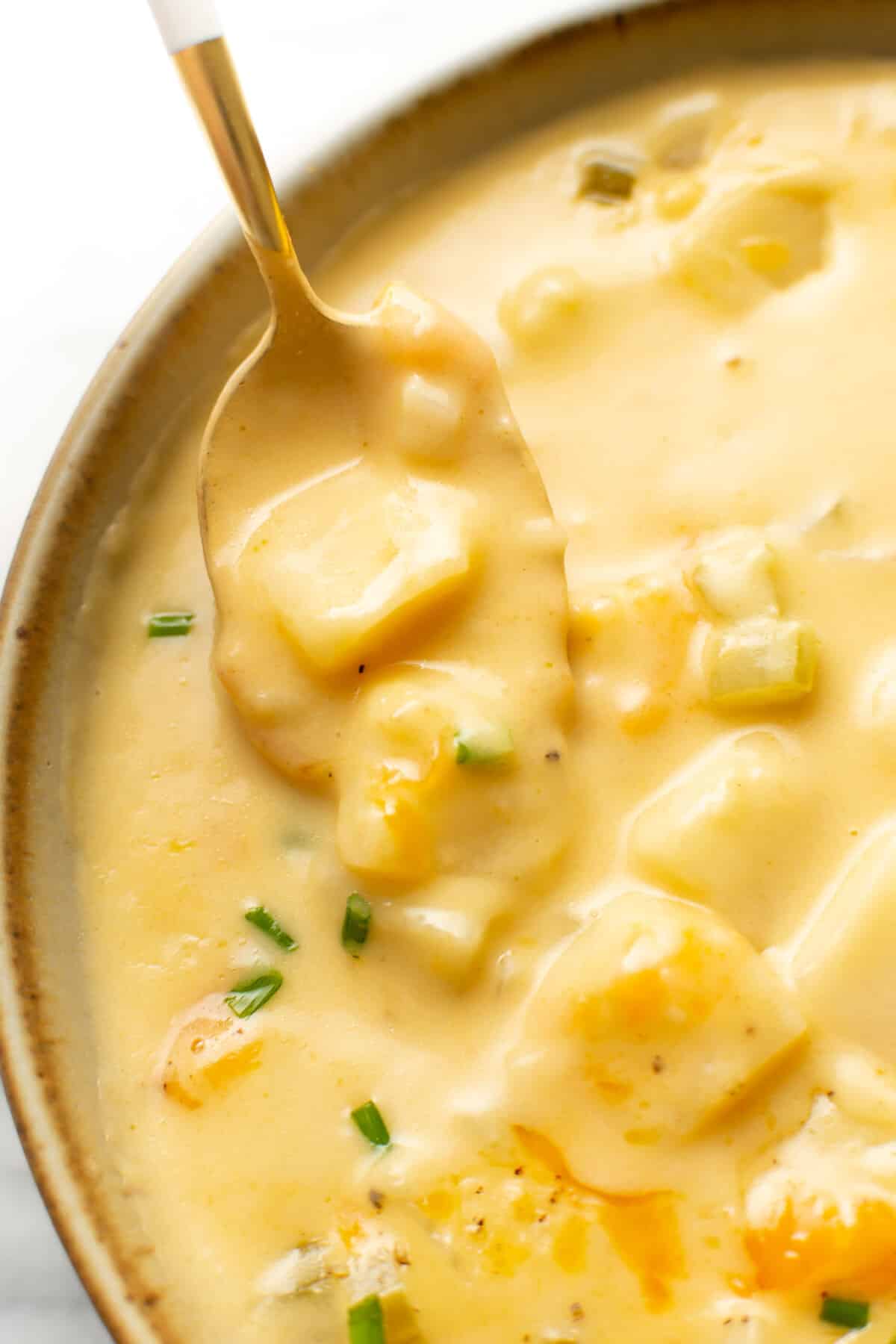 closeup of a bowl of cheesy potato soup with a spoon