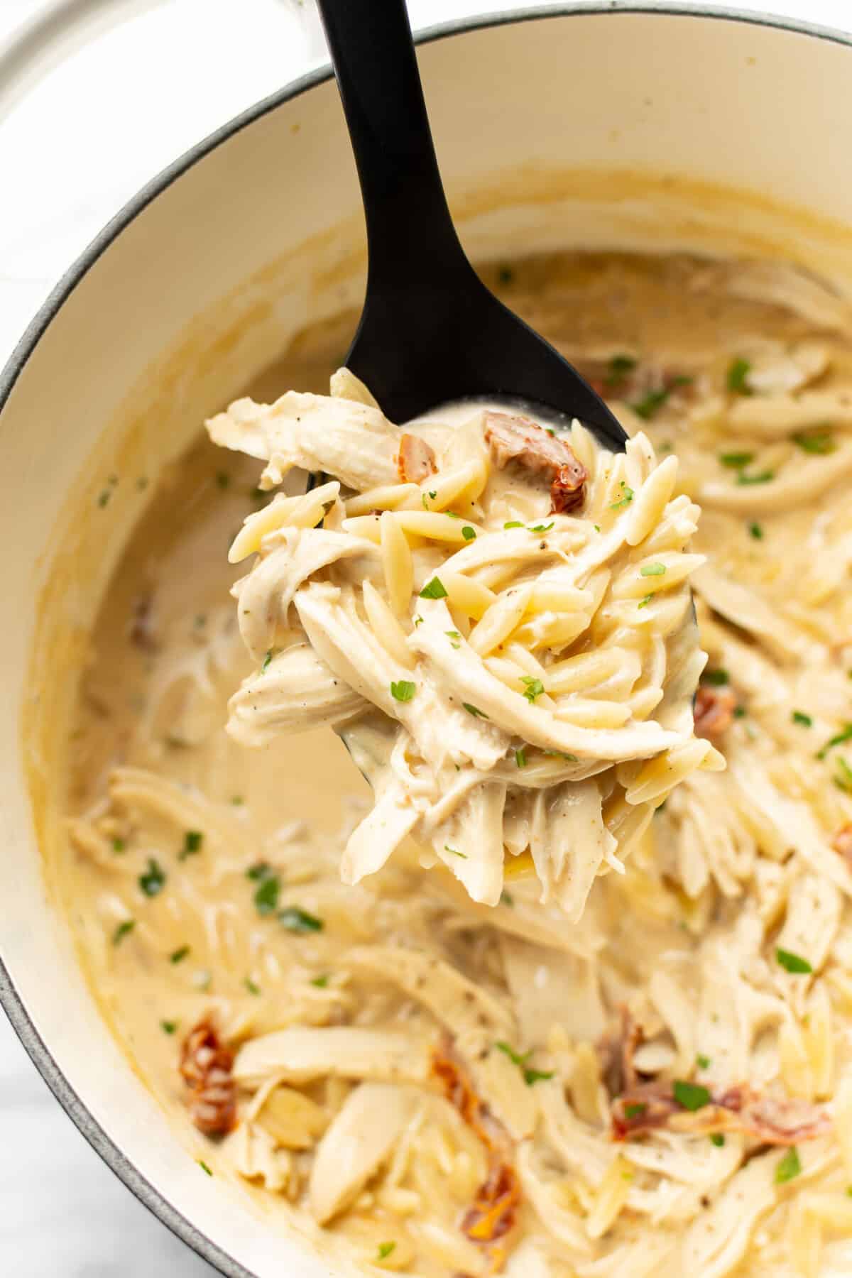 a pot of cajun chicken orzo with a serving spoon