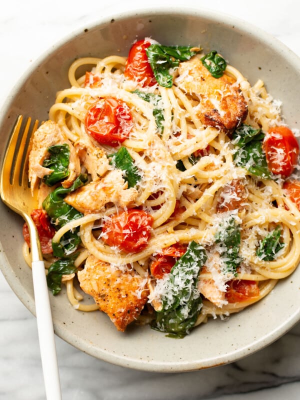 a bowl of tomato spinach salmon pasta with a fork