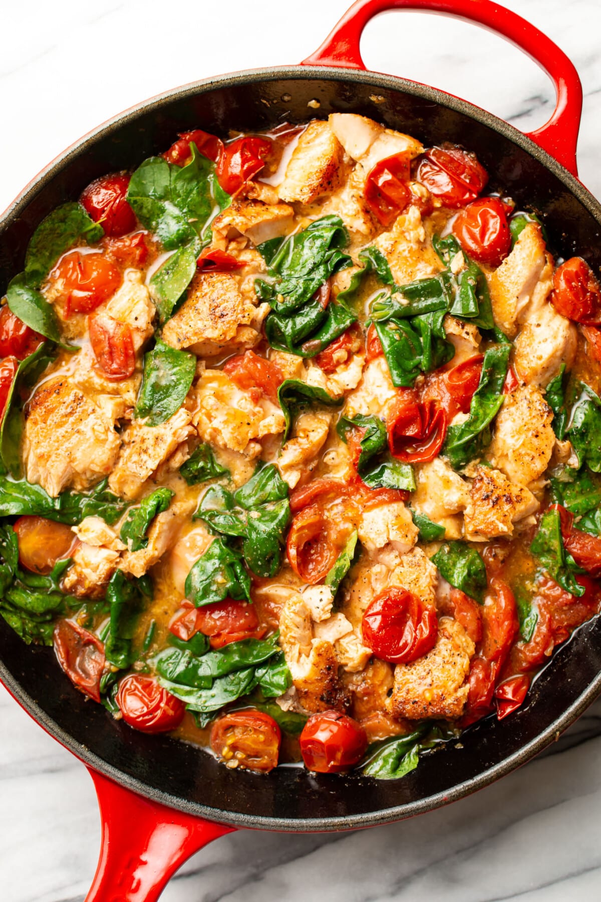 a skillet with salmon and sauce for tomato spinach salmon pasta