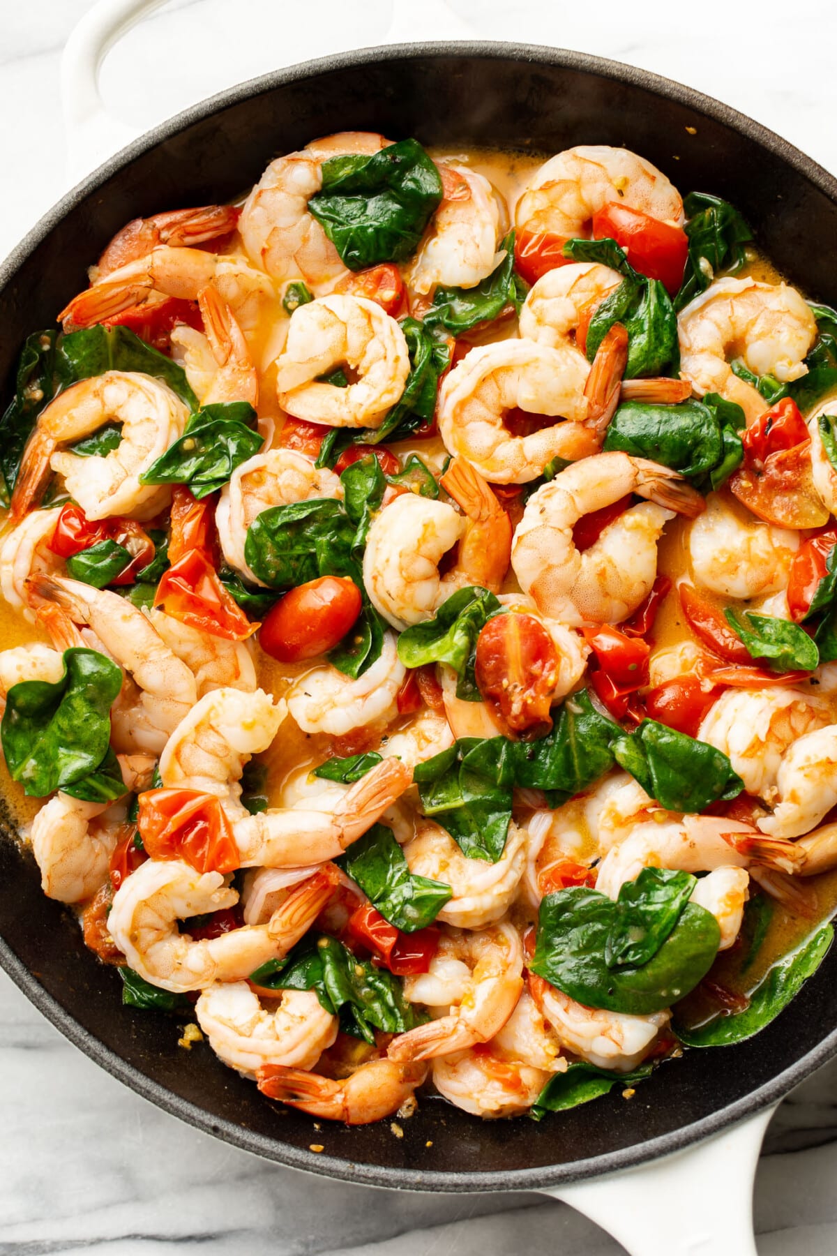 a skillet with sauce for spinach tomato shrimp pasta