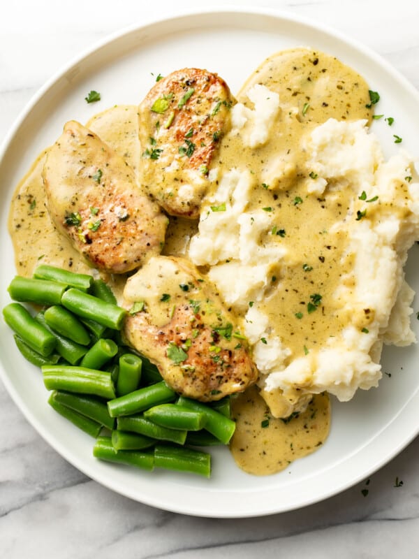 a plate with pesto pork tenderloin, mashed potatoes, and green beans