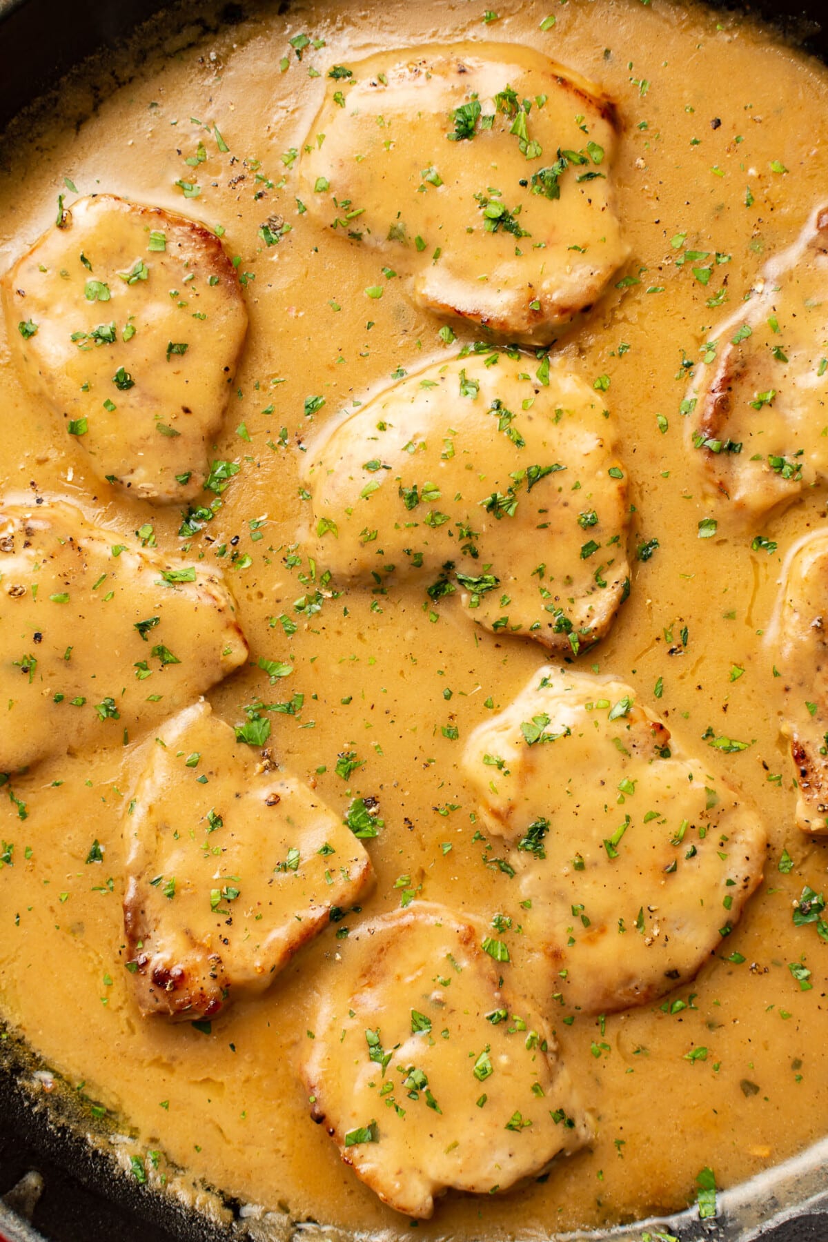 a skillet with several pork tenderloin medallions in ranch gravy