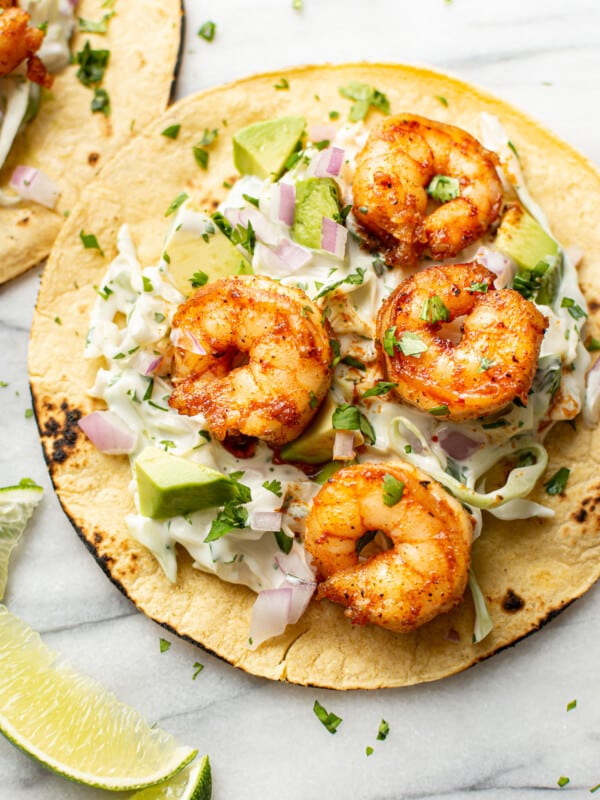 two shrimp tacos with lime wedges