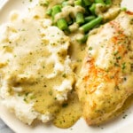 a plate with creamy pesto chicken, mashed potatoes, and green beans