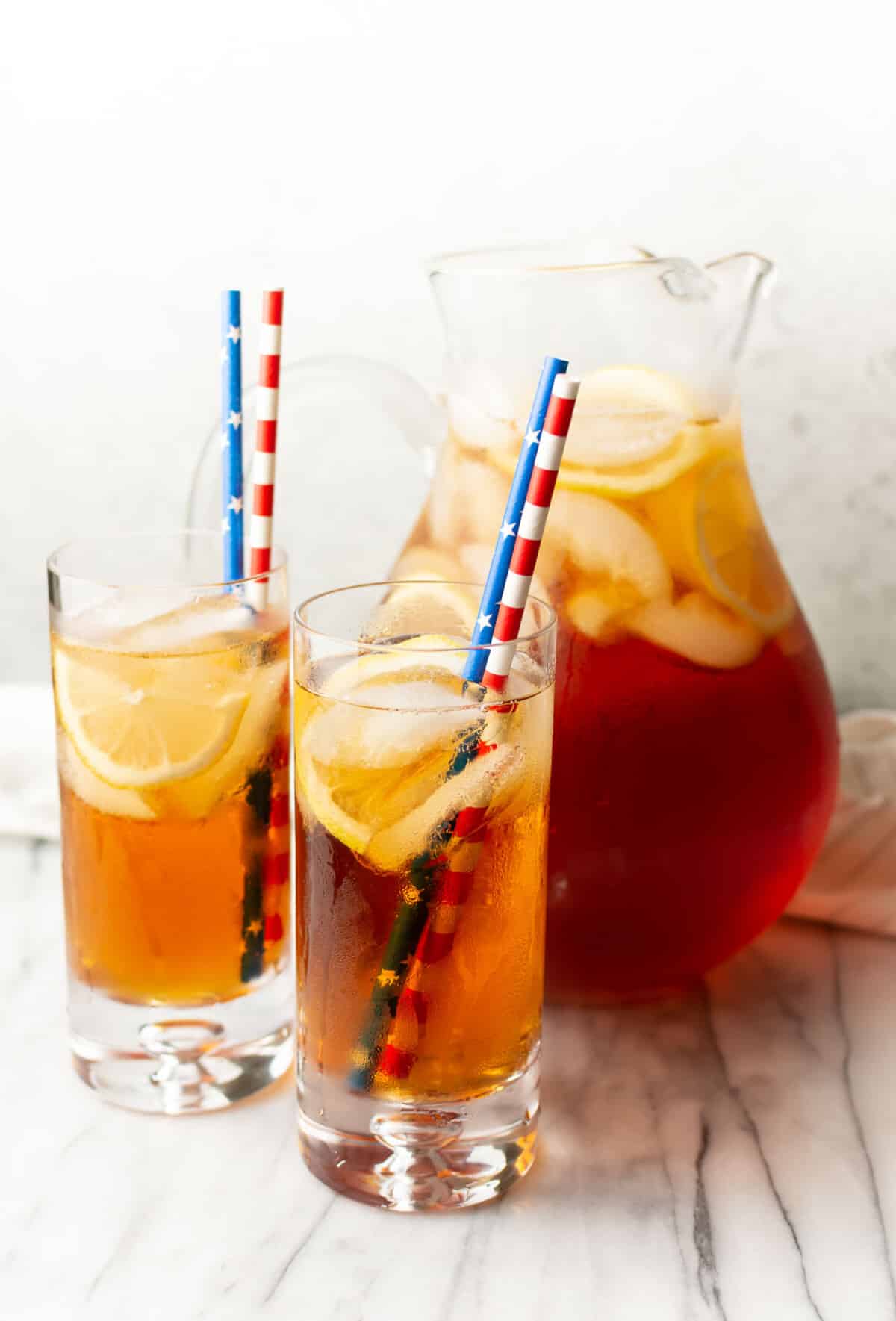 a pitcher of sweet tea with two glasses with straws