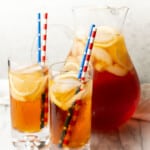 a pitcher of sweet tea with two glasses with straws