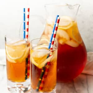 a pitcher of sweet tea with two glasses with straws