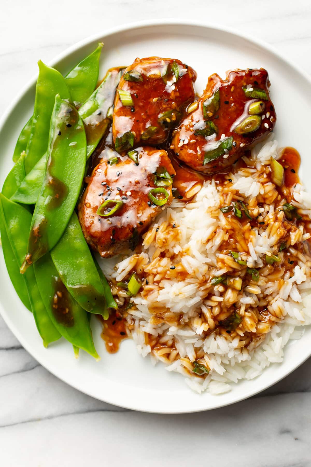 a plate with teriyaki pork tenderloin, rice, and snow peas