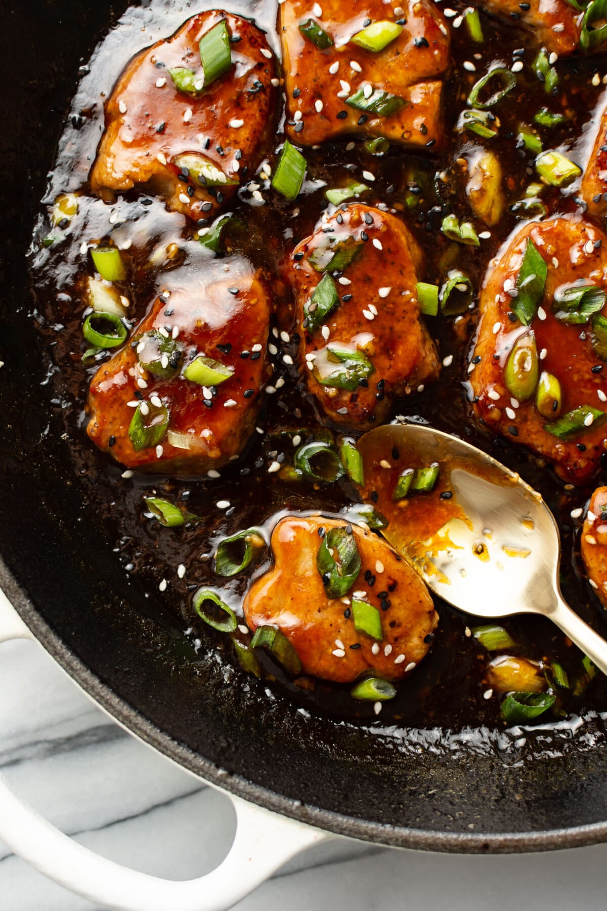 a skillet with teriyaki pork tenderloin and a serving spoon