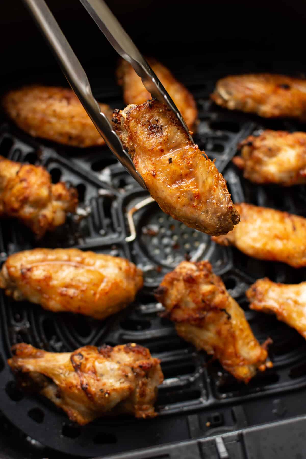 closeup of an air fryer basket with crispy chicken wings