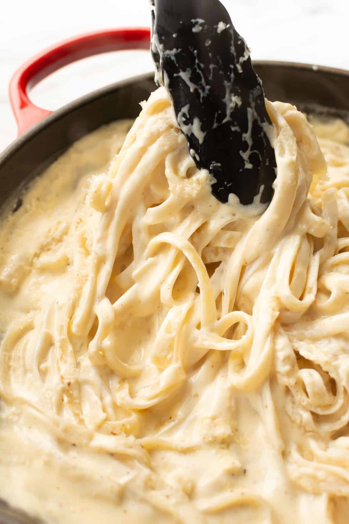 close up of serving tongs with cajun fettuccine alfredo