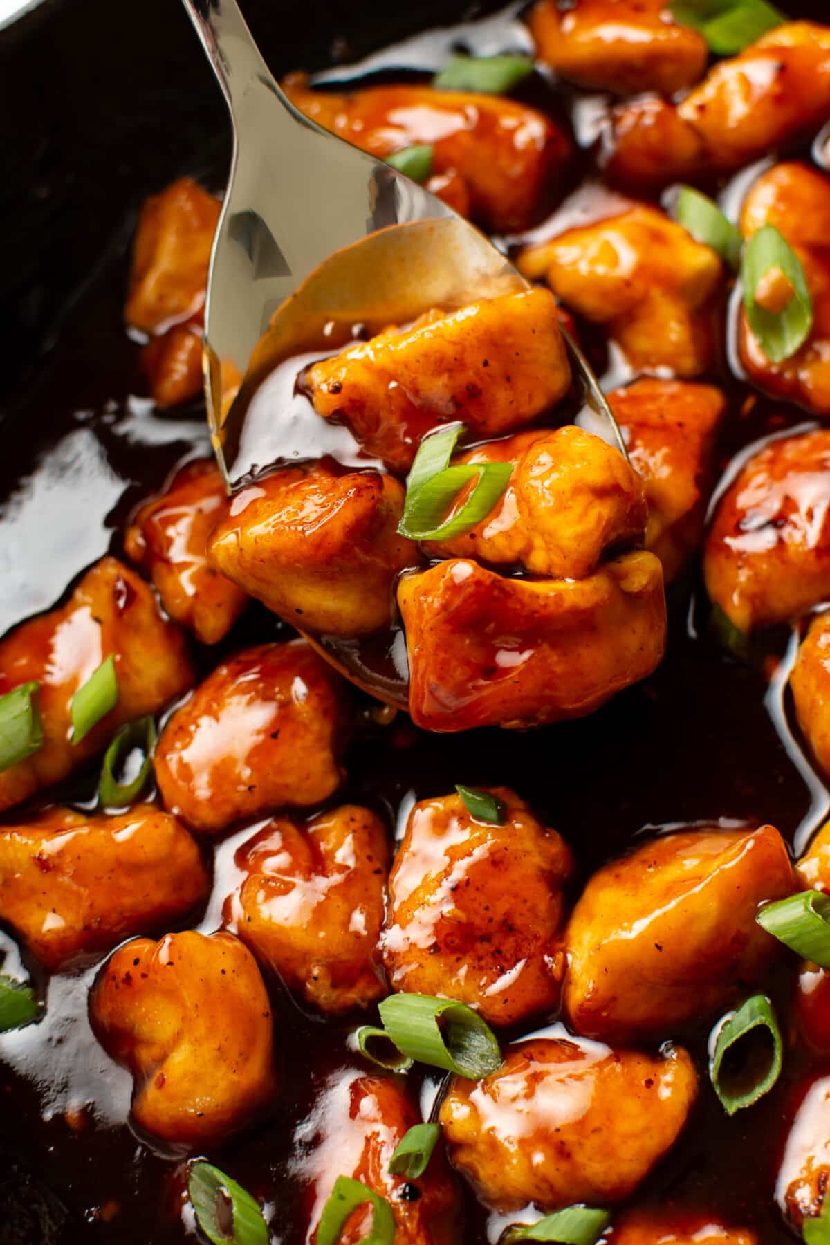 closeup of a skillet with firecracker chicken and a serving spoon