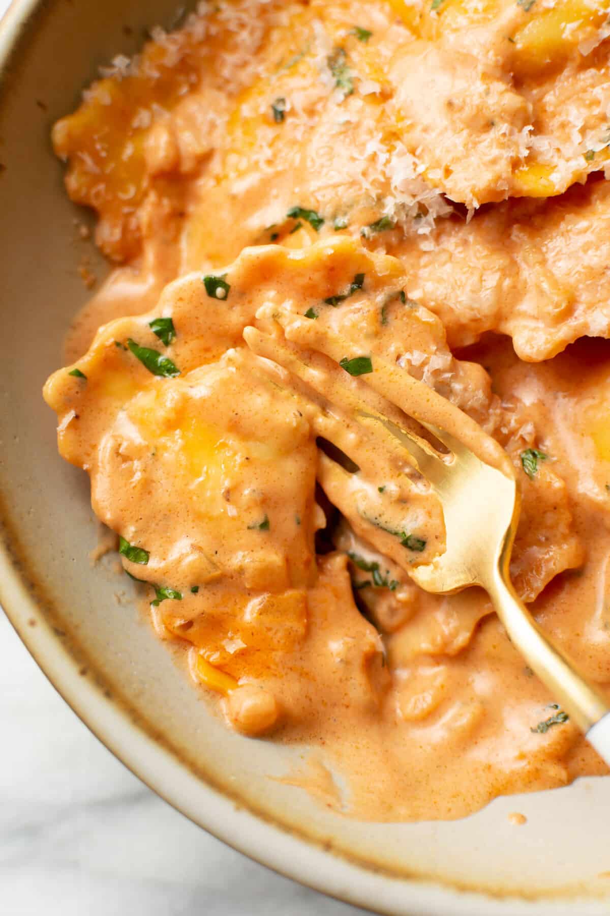 closeup of a bowl of ravioli alla vodka with a fork