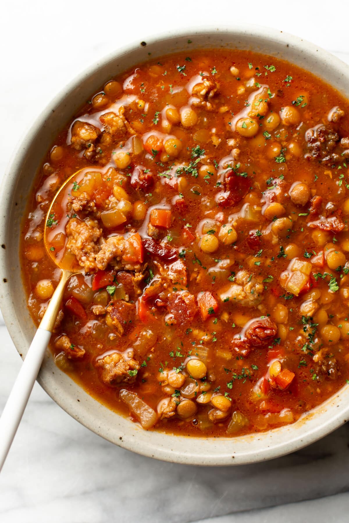 a bowl of sausage and lentil soup with a spoon