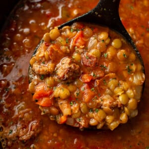 closeup of a slow cooker with sausage and lentil soup and a ladle