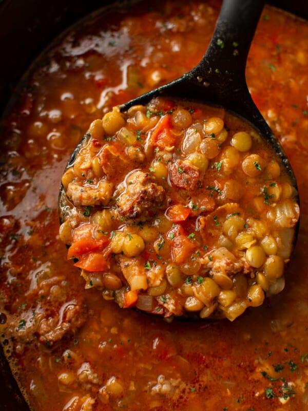 closeup of a slow cooker with sausage and lentil soup and a ladle