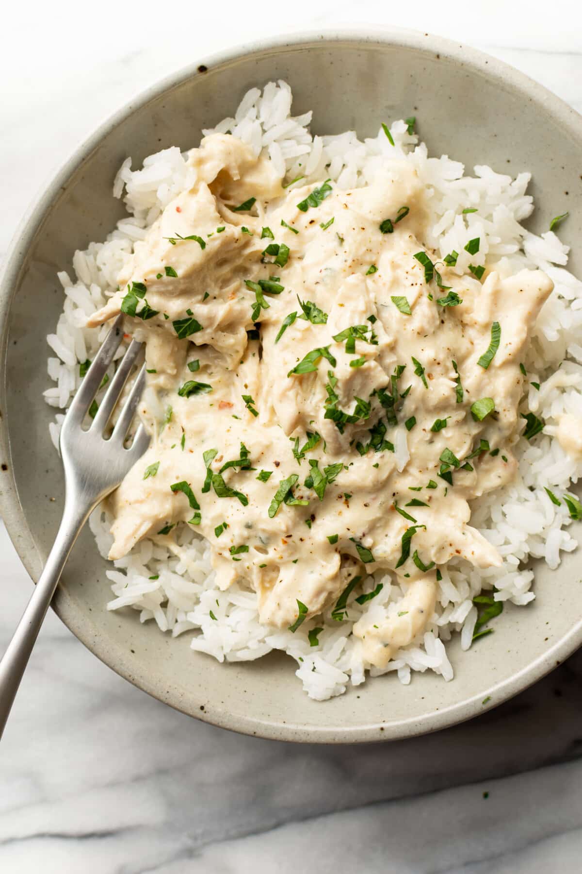 a bowl of crockpot italian chicken over rice with a fork