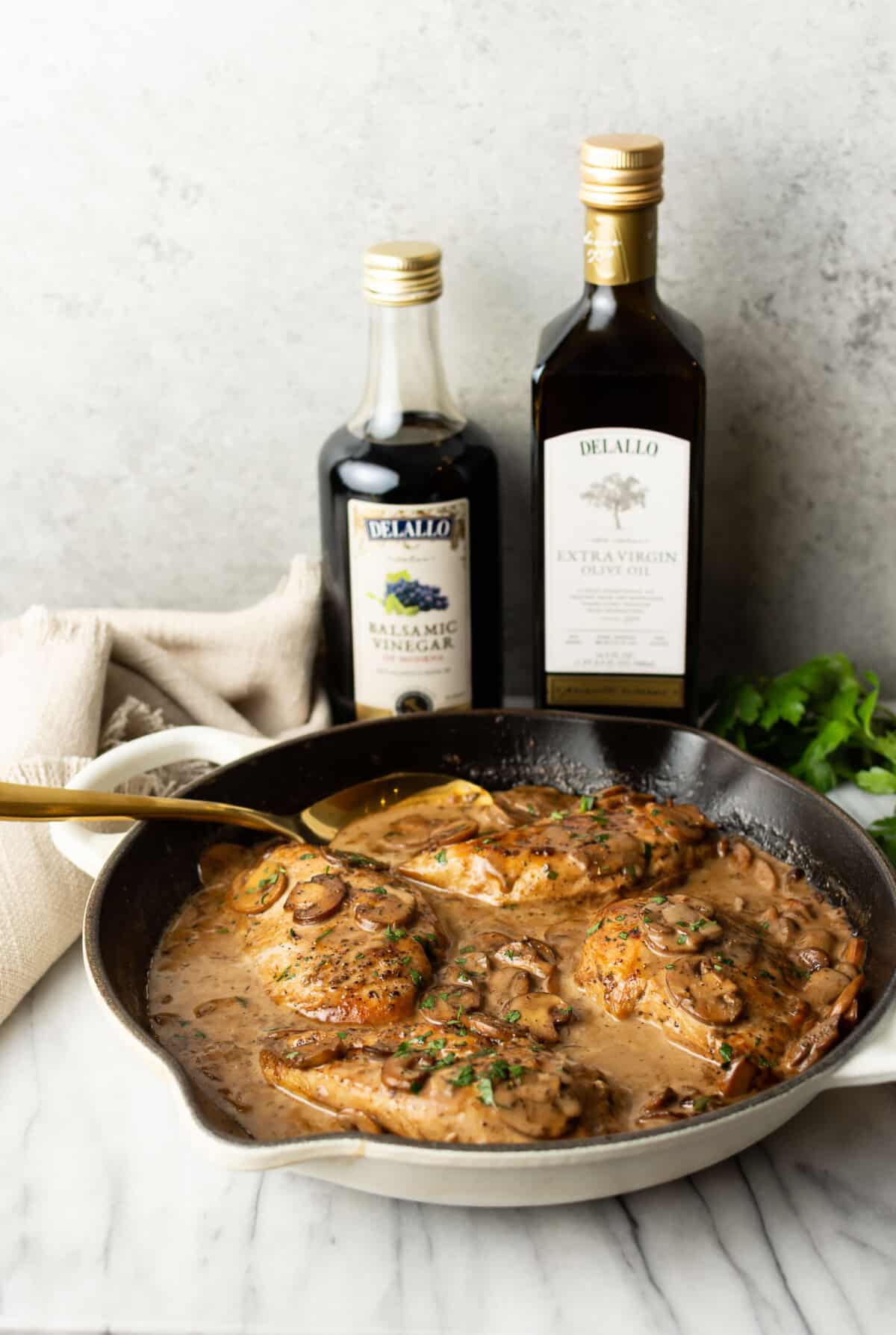 a skillet with balsamic chicken next to bottles of olive oil and vinegar