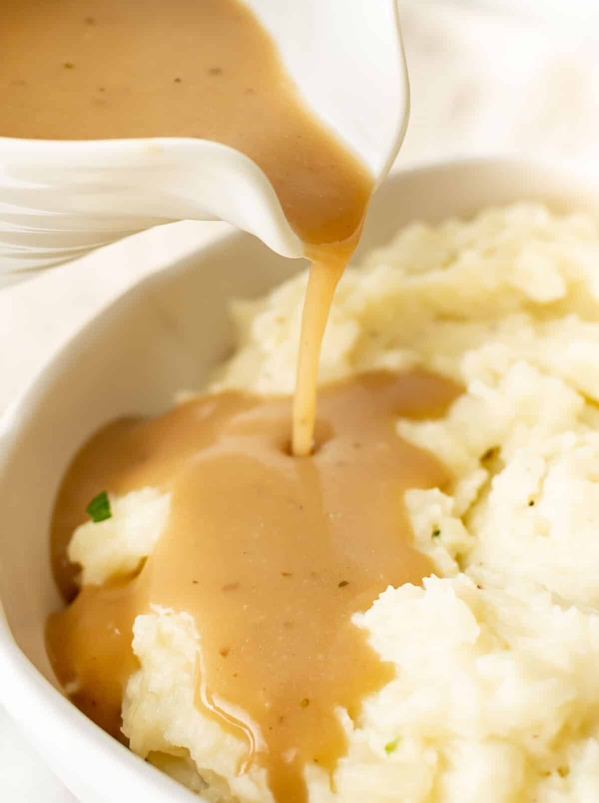 pouring brown gravy onto mashed potatoes