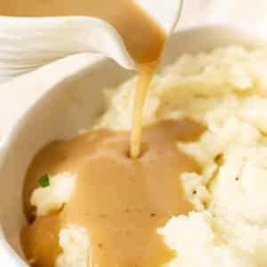 pouring brown gravy onto mashed potatoes