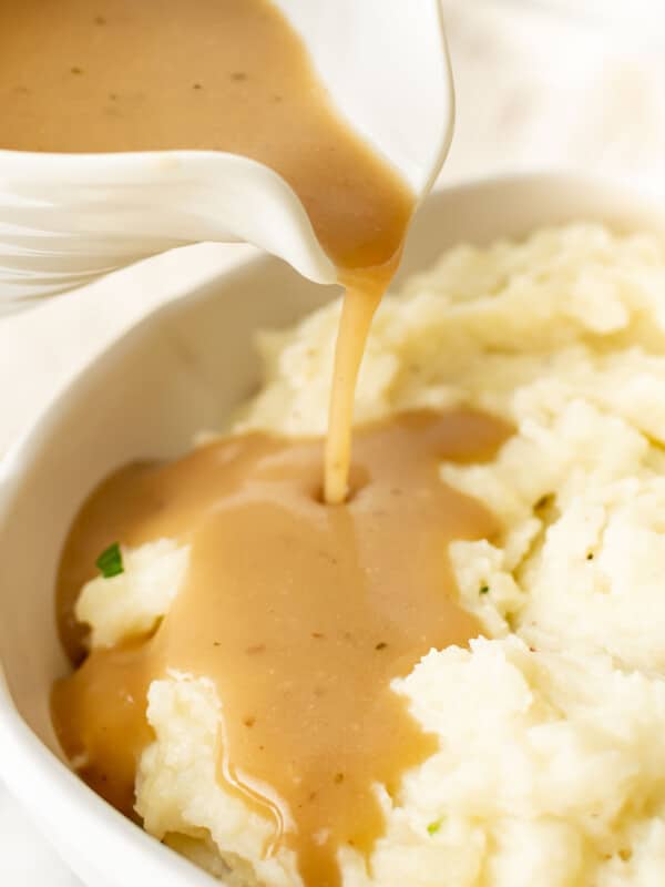 pouring brown gravy onto mashed potatoes