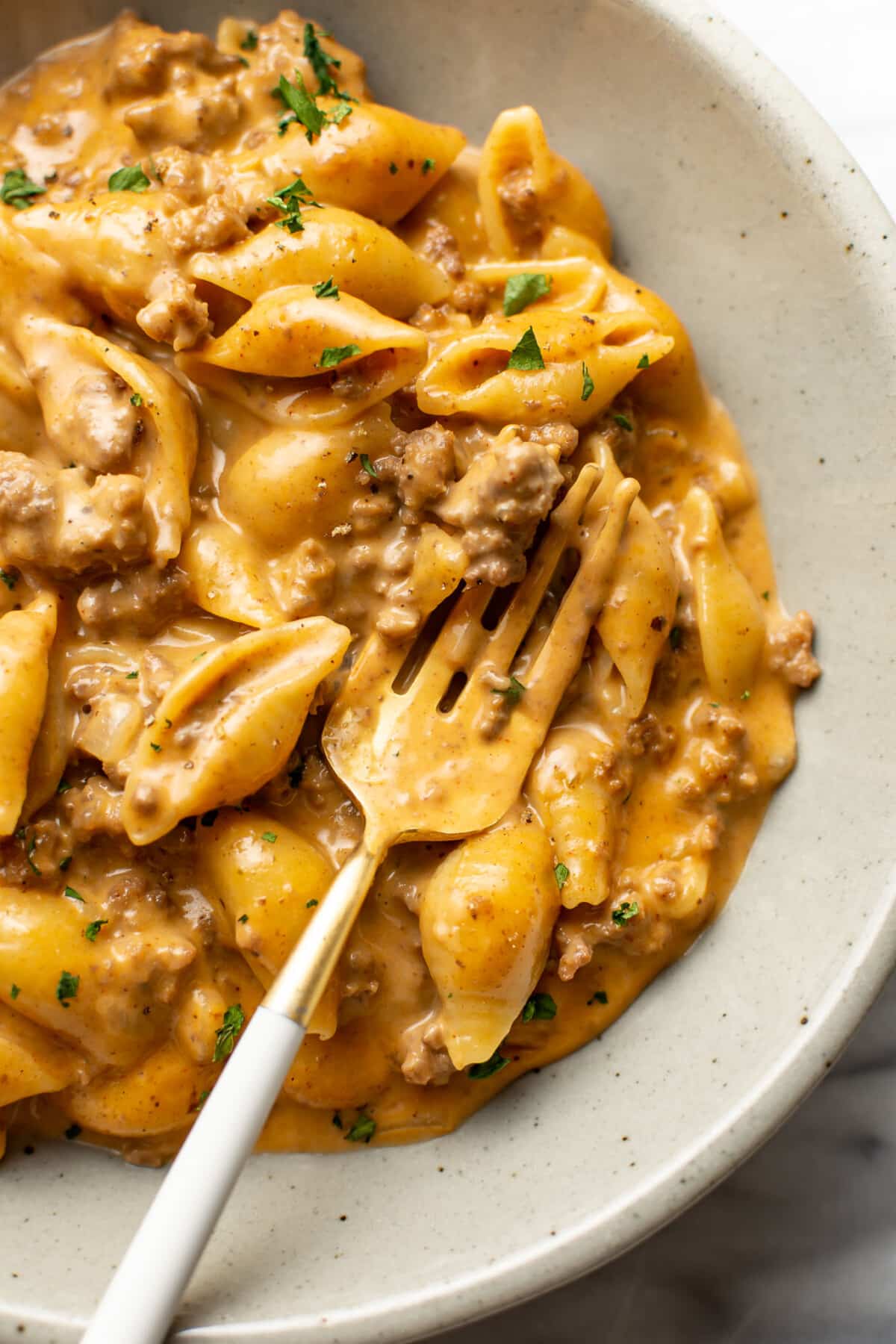 a bowl with cheesy beef and shells and a fork