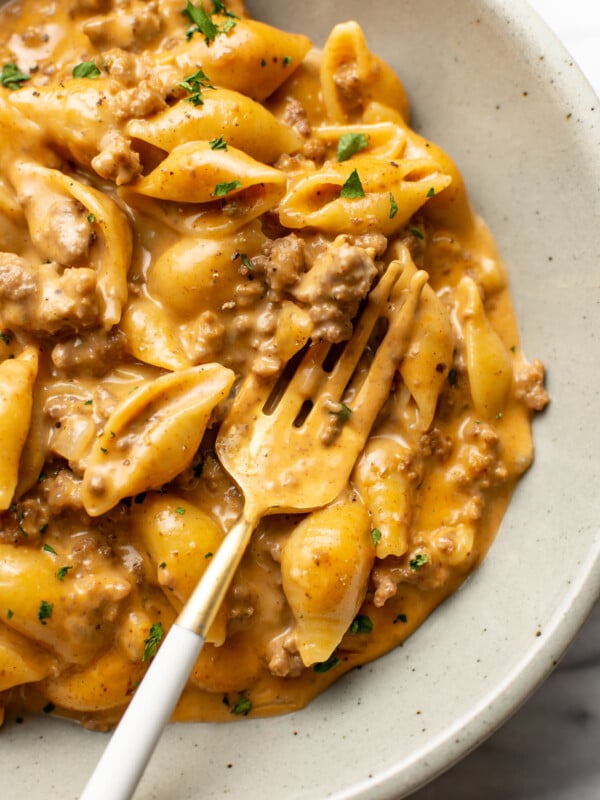 a bowl with cheesy beef and shells and a fork