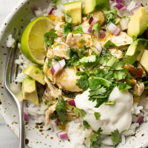 a bowl with crockpot salsa verde chicken over rice and a fork